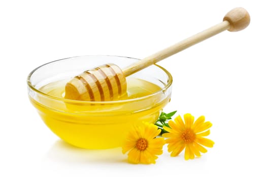 Sweet honey pouring from wooden dipper in glass bowl isolated on white