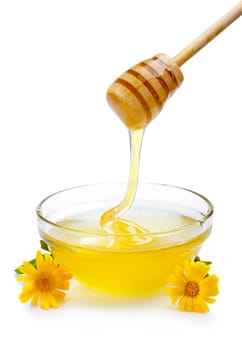 Sweet honey pouring from wooden dipper in glass bowl isolated on white
