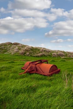 lush green field on the coast with an abandoned agricultural heavy roller