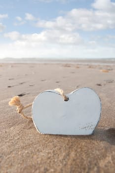 single wooden love heart in the sand on a wild Atlantic way Irish beach in summer with copy space