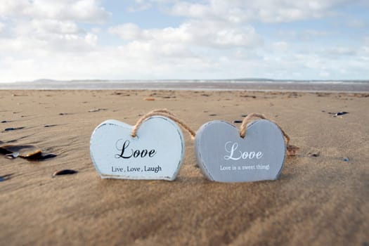 two inscribed wooden love hearts in the sand on a wild Atlantic way Irish beach in summer