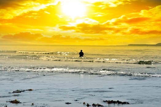 man fishing among the waves of the Atlantic ocean in Ballybunion county Kerry Ireland