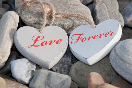 two wooden love hearts on the rocks of a beach
