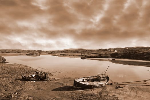 two old fishing boats beached on a coastal beach in county Donegal, Ireland in sepia