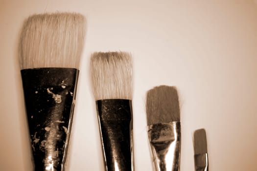 collection of various artists brushes in all sizes on a canvas background in sepia