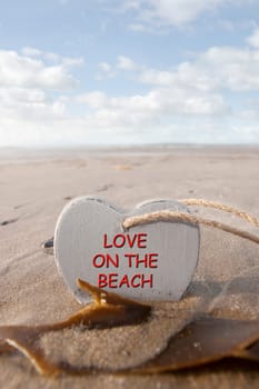 single wooden love heart in the sand on a wild Atlantic way Irish beach in summer with copy space