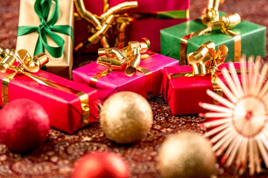 Plain presents between Christmas ornaments and straw stars. Seasonal background with shallow depth of field. Rich in textures..