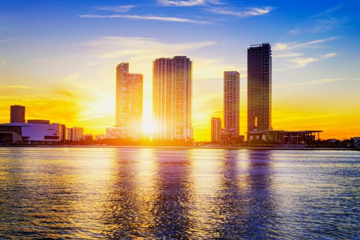 Miami city skyline panorama at dusk with urban skyscrapers over sea with reflection