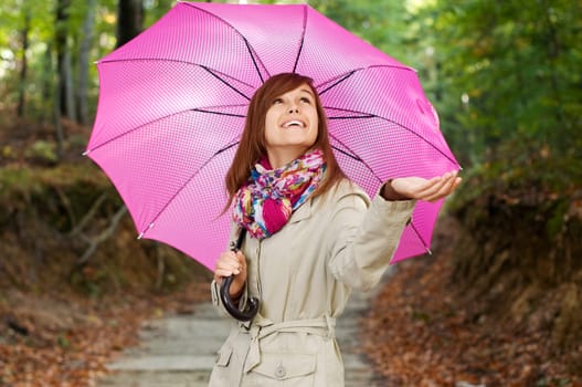 Beautiful girl with umbrella checking for rain