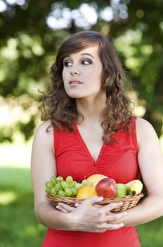 Young woman holding basket filled mix fruit