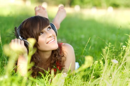 Young woman listening music on grass
