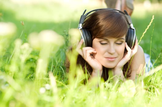 Young woman listening music on grass