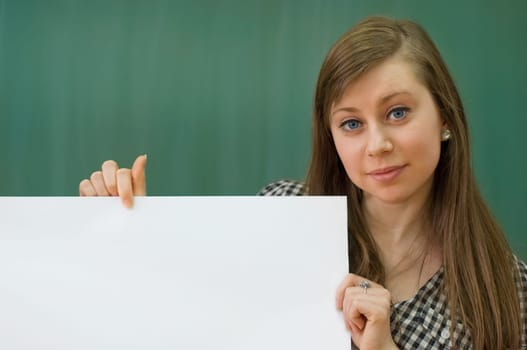 Young woman in classroom holding white blank billboard