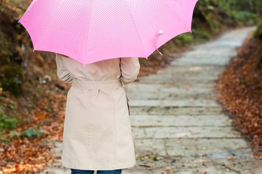 Young woman with umbrella walking through the park