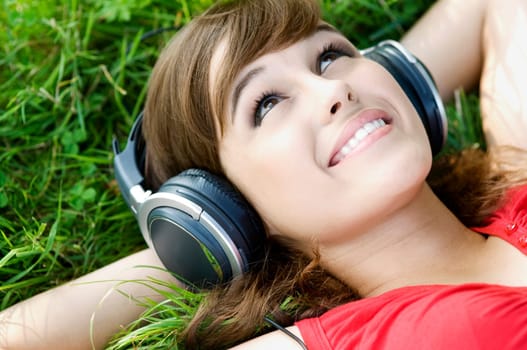 Young woman listening music on grass