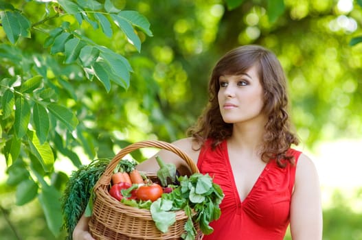 Young woman holding basket filled vegetables