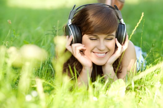 Young woman listening music on grass