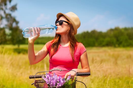 Active woman with bike drinking cold water