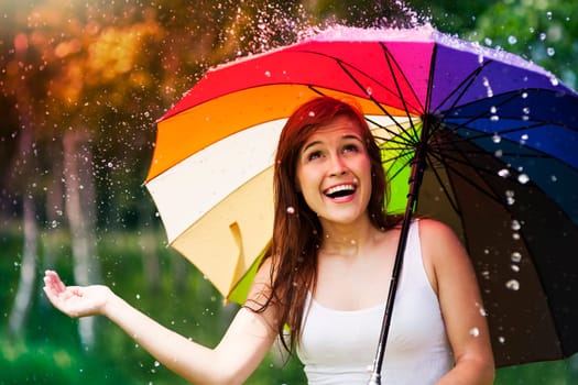 Surprised woman with umbrella during summer rain