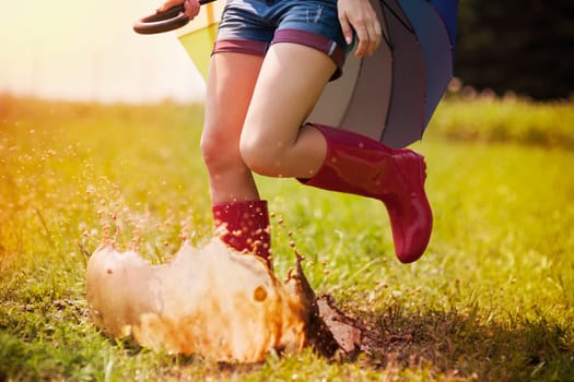 Jumping woman with umbrella and rubber boots