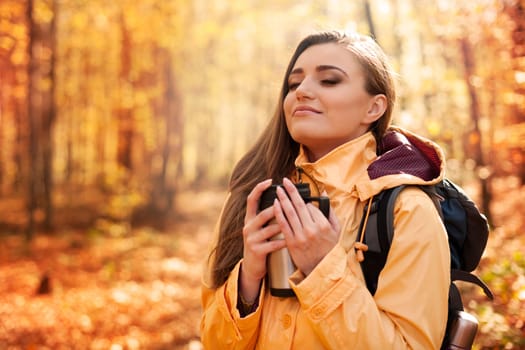 Smiling female hiker has a break for hot drink