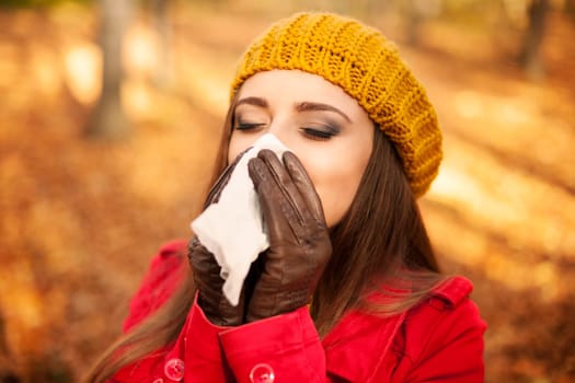 Woman sneezing in handkerchief at autumn