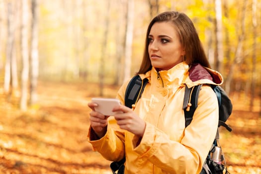 Confused young hiker with smart phone in forest