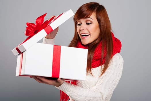 Surprised young woman peeking into the christmas gift