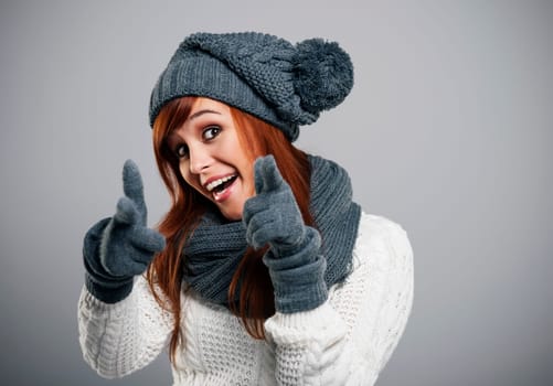 Young woman wearing warm clothes pointing at camera