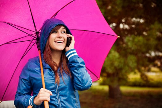 Young woman with mobile phone on rainy day