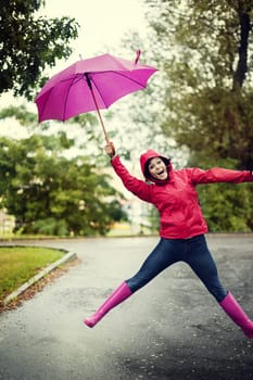 Cheerful woman jumping with umbrella