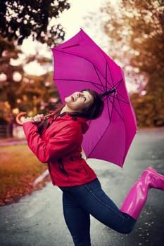 Cheerful woman with umbrella and rubber boots in the rain