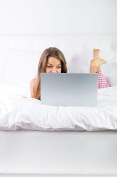 Young woman using laptop in bed