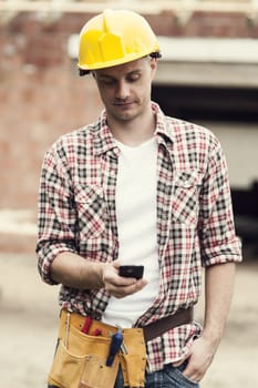 Construction worker texting on mobile phone