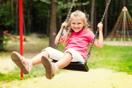 Happy girl swinging on playground