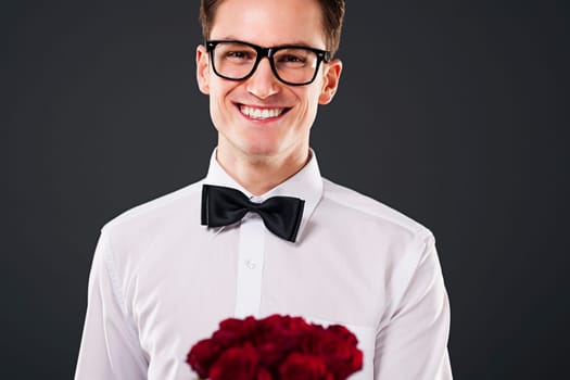 Man wearing on glasses holding bouquet of red roses
