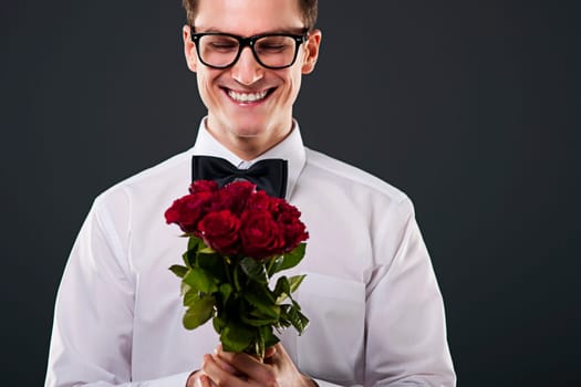 Man with glasses holding red roses