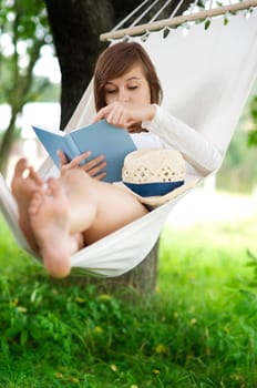 Young woman reading a book on hammock