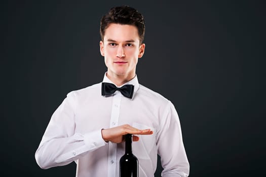 Focused waiter holding a bottle of wine