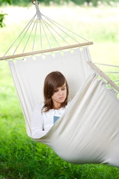 Young woman reading a book in hammock
