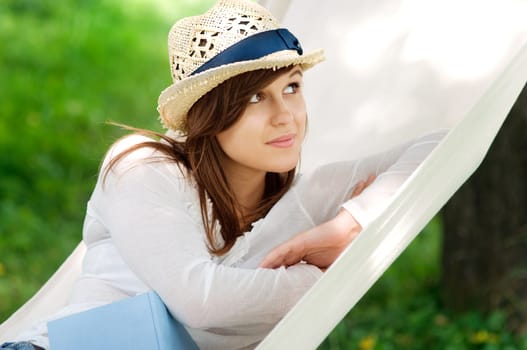Young woman relaxing in a hammock with book