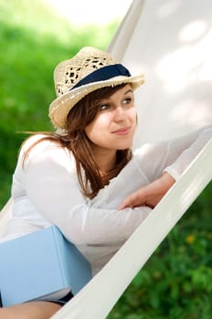 Young woman relaxing in a hammock with book