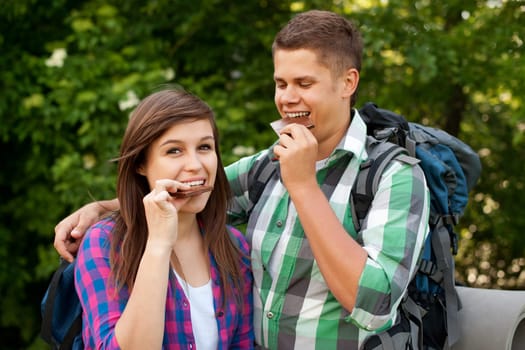 Young couple eating chocolate in forest