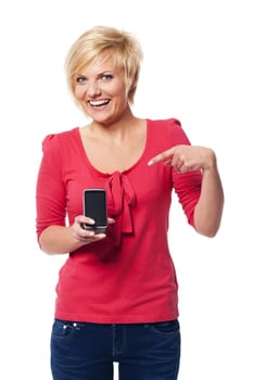 Smiling young woman pointing at screen of mobile phone