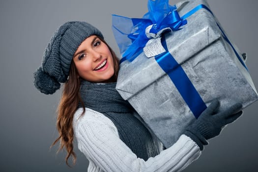 Happy woman wearing warm clothing holding big present