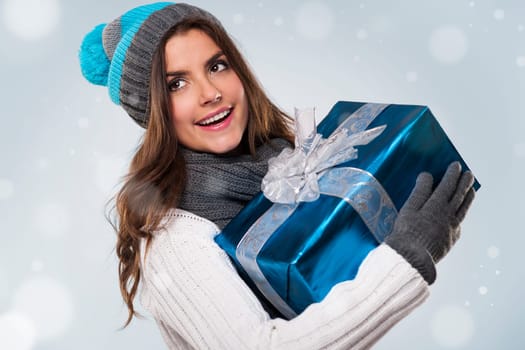 Beautiful woman during the magic christmas time with blue gift