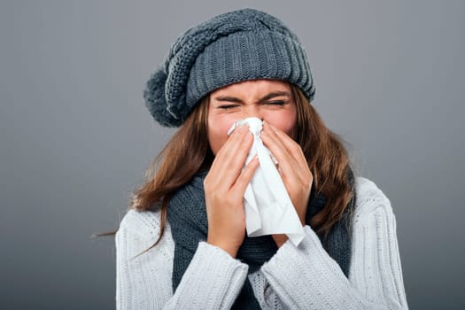 Woman in winter clothes sneezing