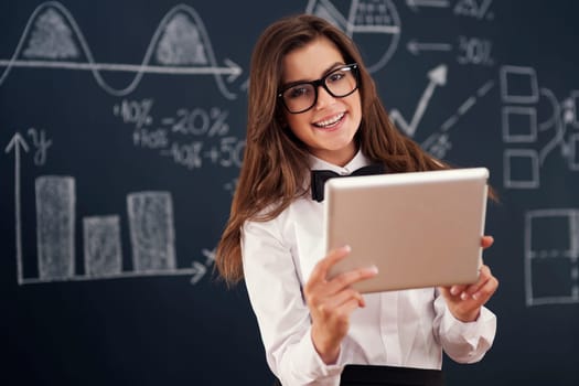 Smiling  teacher using digital tablet in classroom