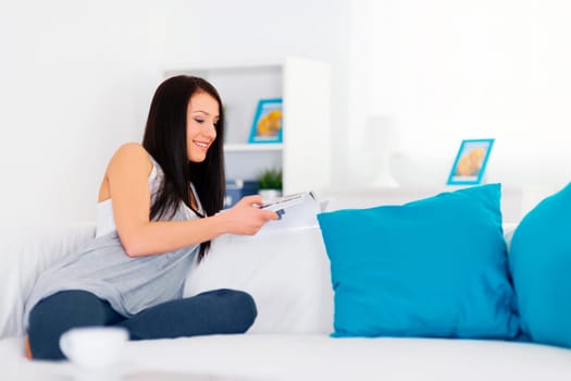 Brunette on sofa reading magazine