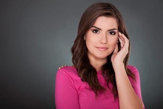 Beautiful young woman smiling on grey background